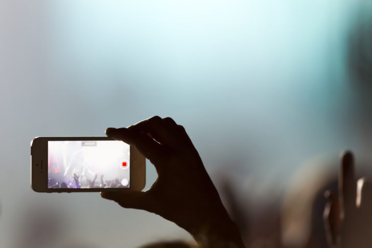 People taking photographs with touch smart phone during a music entertainment public concert