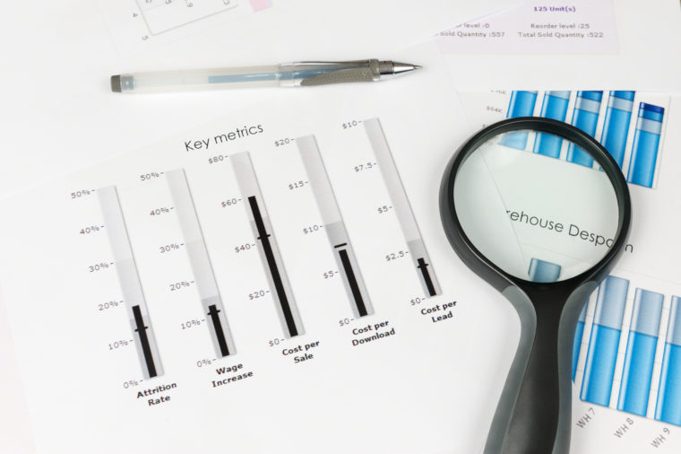 Business graph printed on the white paper with a magnifier on it