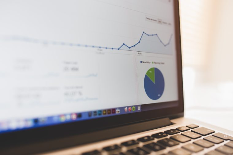 Image of a partially blurred laptop screen with a line graph and pie chart beneath the line graph