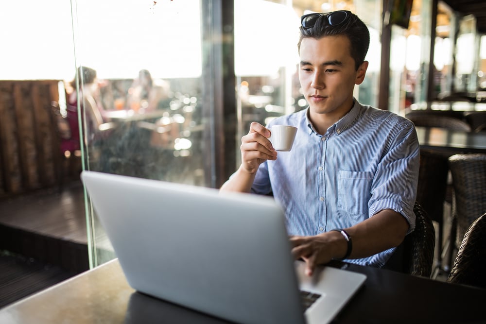 man-using-a-laptop-while-drinking-coffee