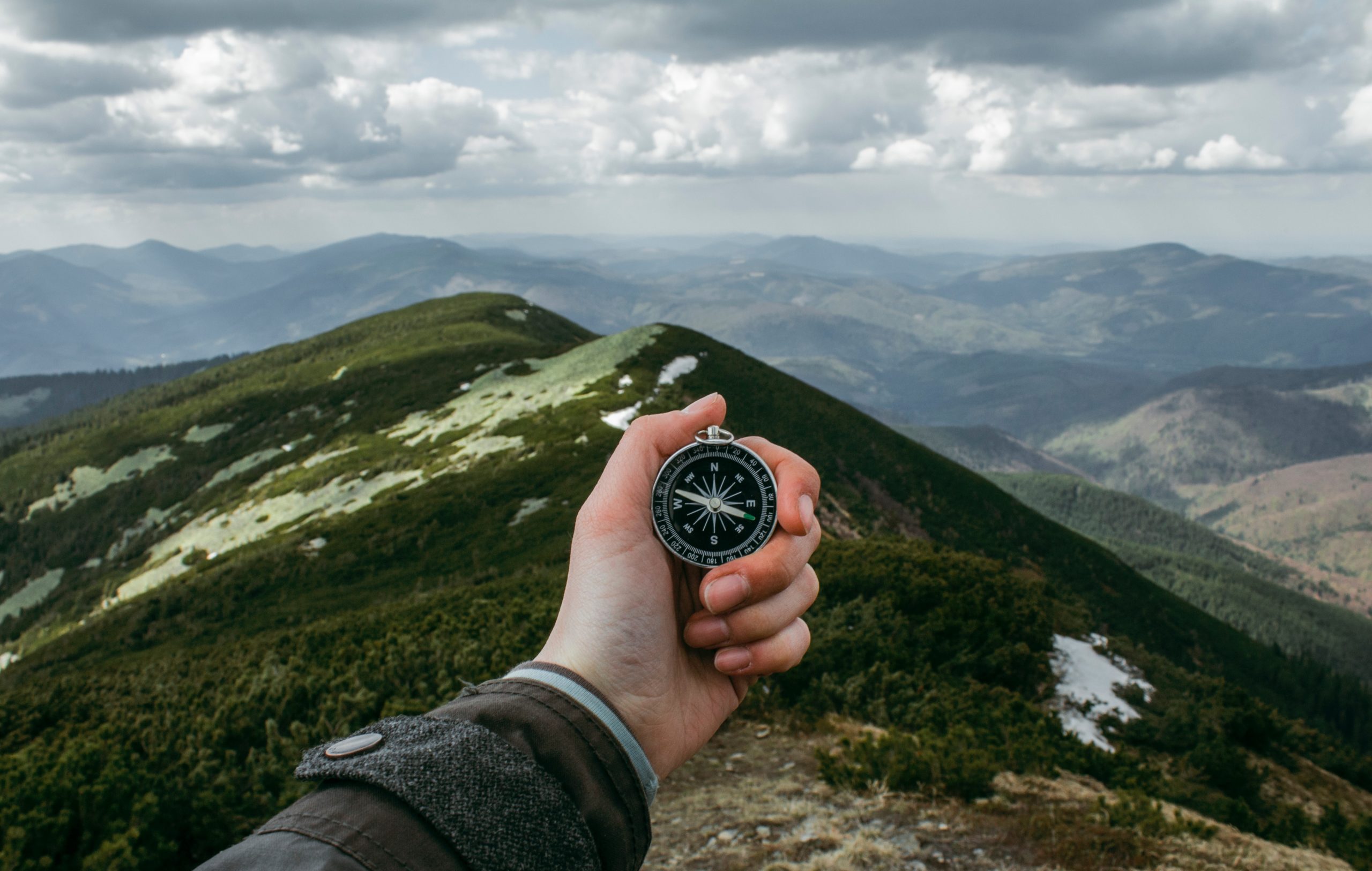 Someone with a compass, standing on a mountain figuring out the way to go