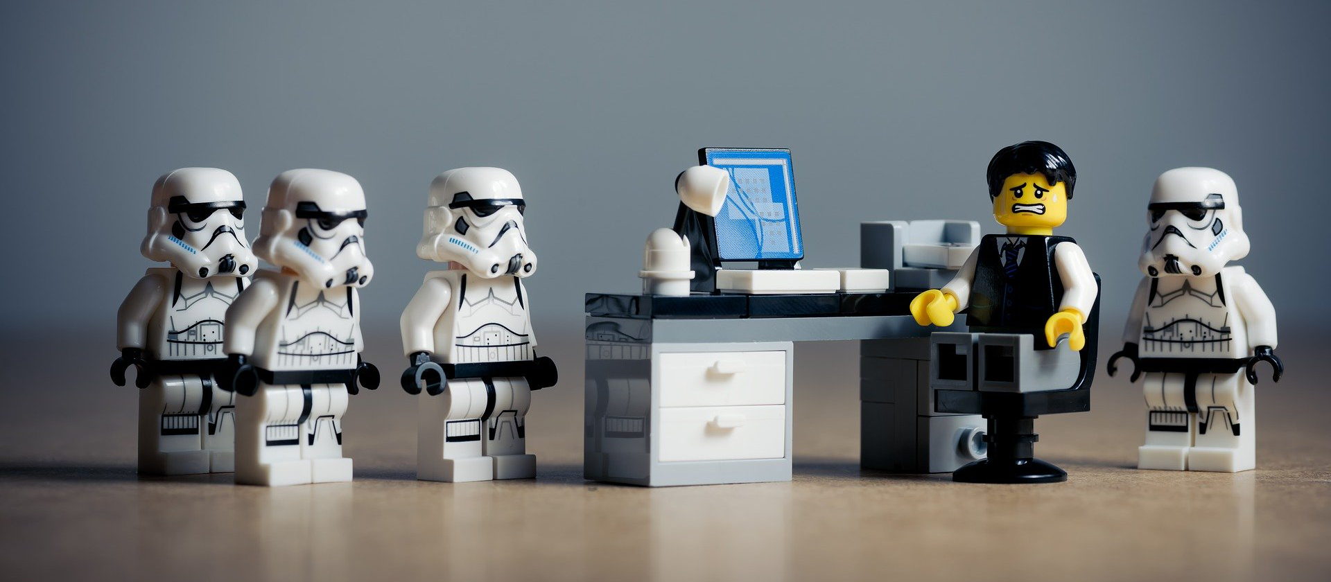 LEGO stormtroopers surrounding someone at a desk