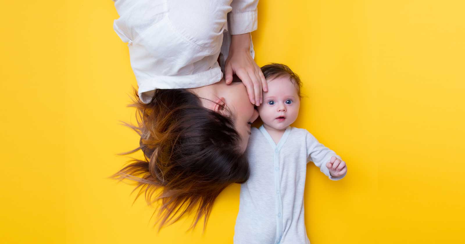 Image of a mother whispering into an infant's ear