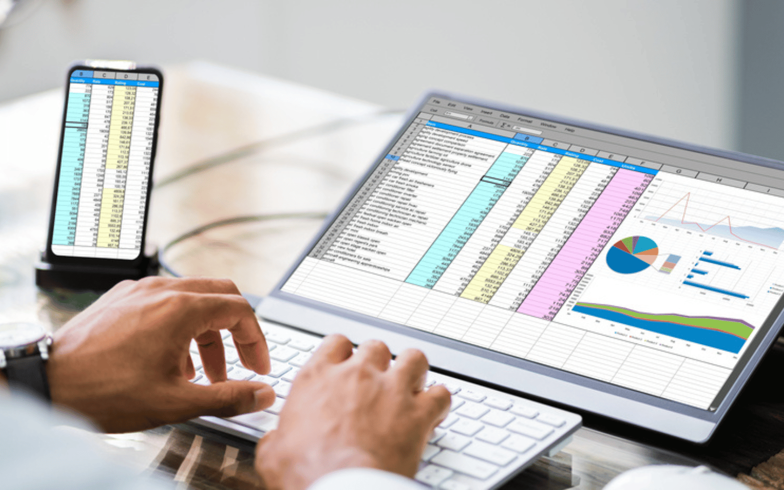 A professional working on a laptop with Awesome Spreadsheet Apps and charts displayed on the screen while also viewing similar data on an iPhone in hand.