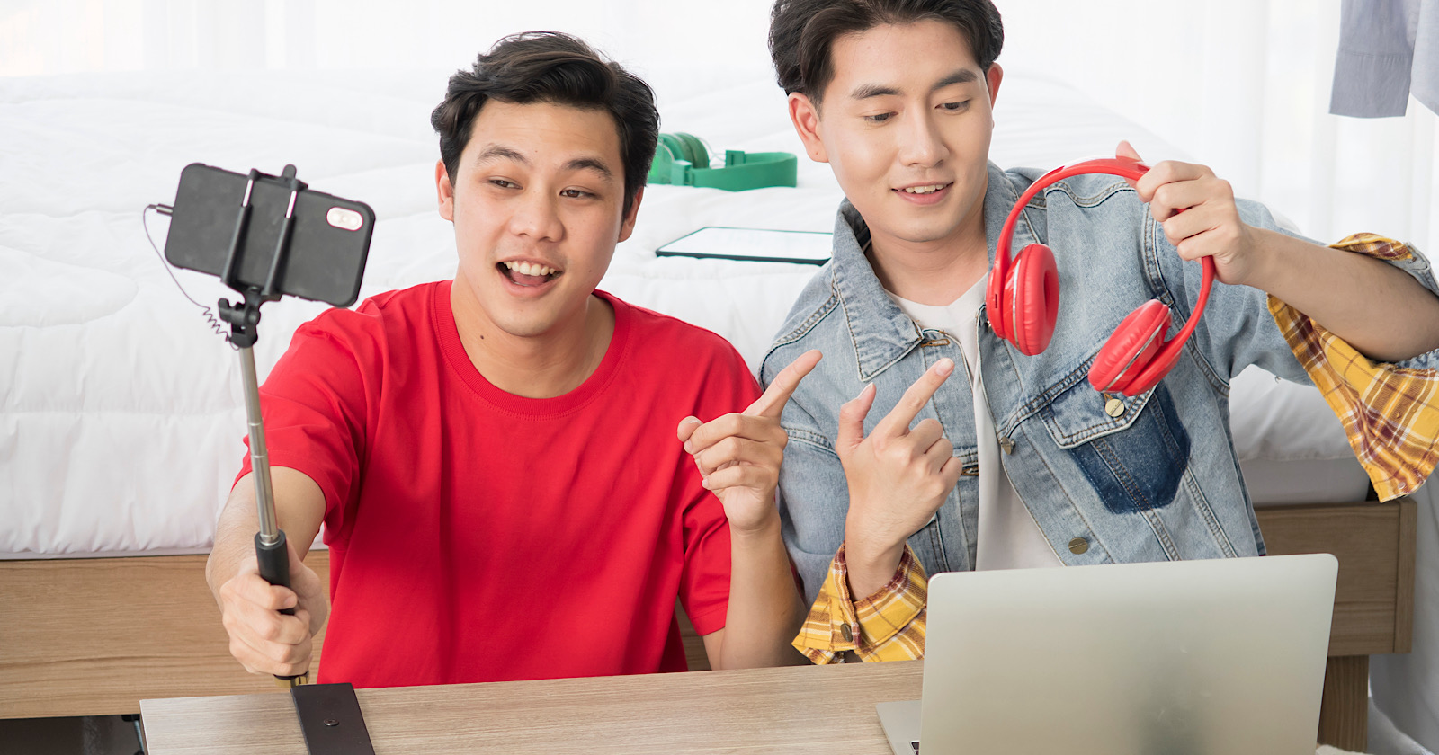 Two happy Young Asian men influence blogger present and review product on live streaming broadcast with internet subscribers. Social media people content maker,