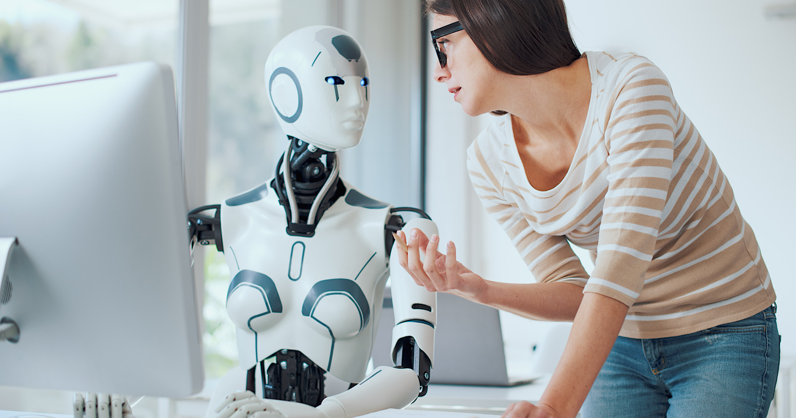 Woman and AI robot working together in the office, automation and technology concept