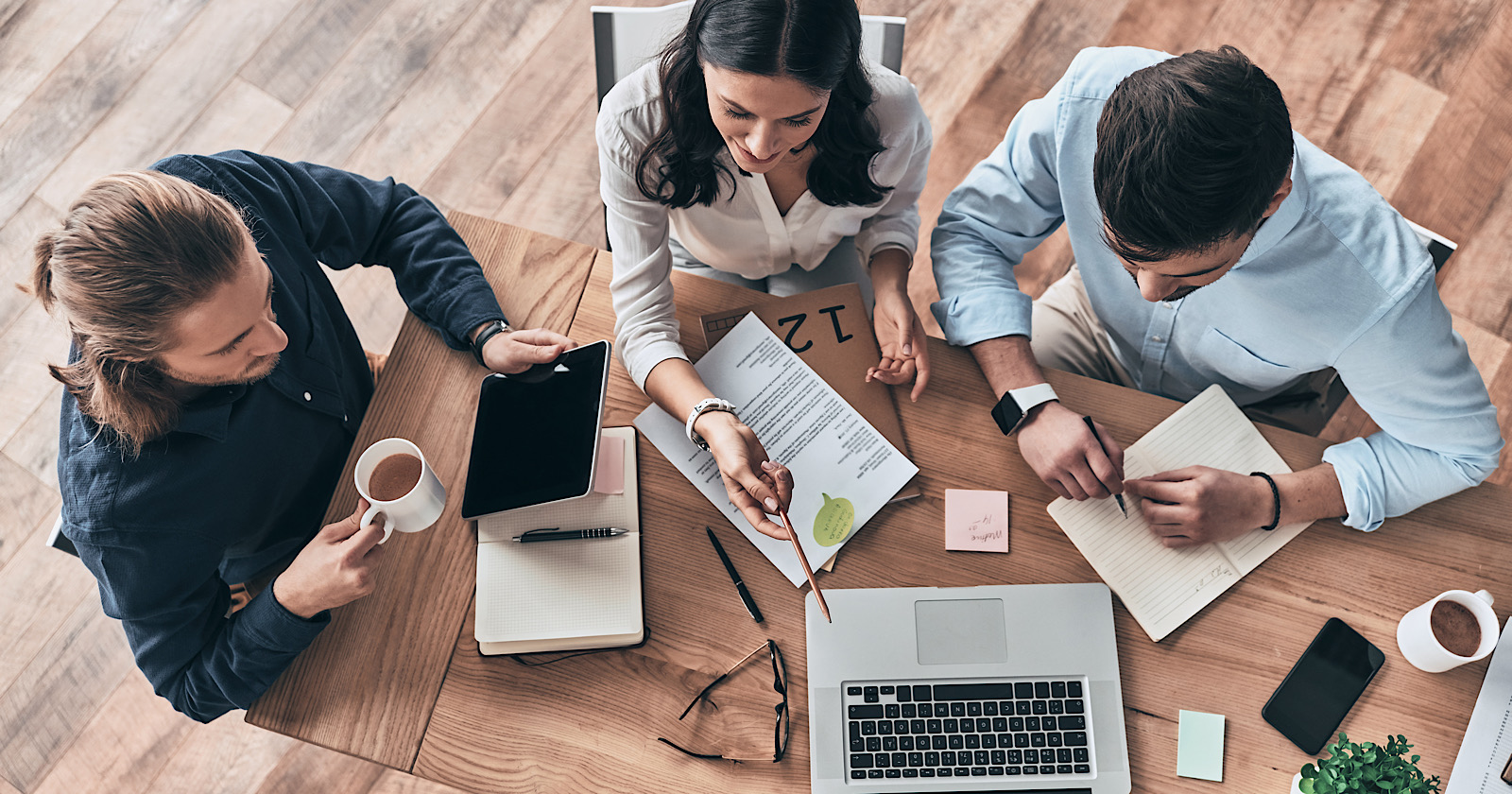 Talking about business details. Top view of young modern colleagues in smart casual wear working together while spending time in the office