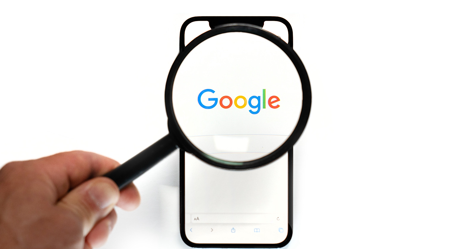 Google logo on a smartphone viewed through a magnifying glass